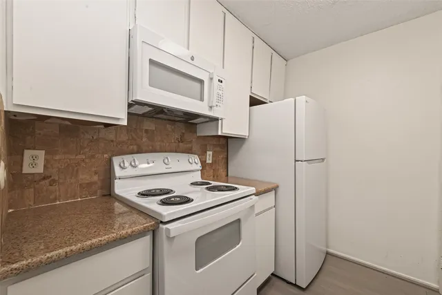 a kitchen with stainless steel appliances granite countertop white cabinets a refrigerator and a stove