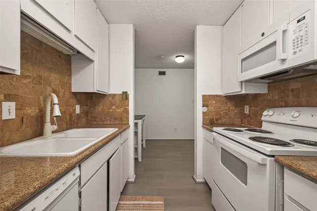 a kitchen with granite countertop a sink stove and cabinets