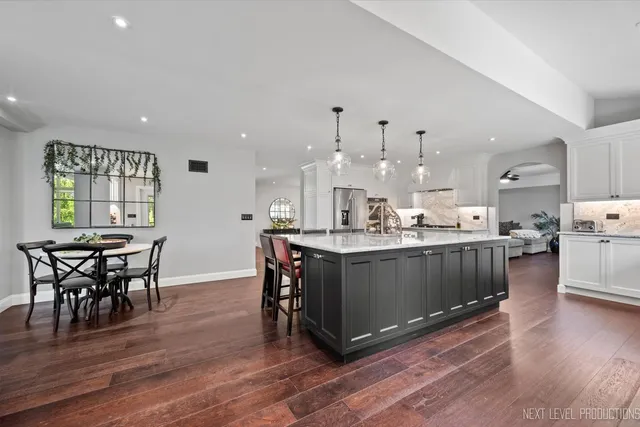 a kitchen with stainless steel appliances kitchen island hardwood floor sink stove dining table and chairs