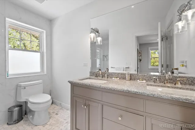 a bathroom with a granite countertop toilet sink and mirror