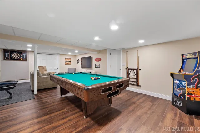a room with furniture pool table wooden floor and windows
