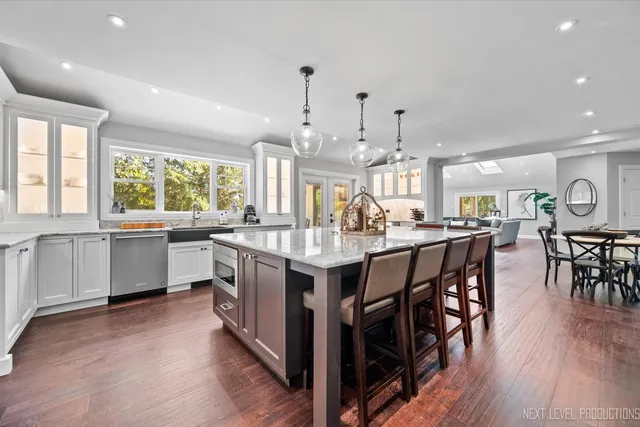 a kitchen with stainless steel appliances granite countertop wooden floors and white cabinets