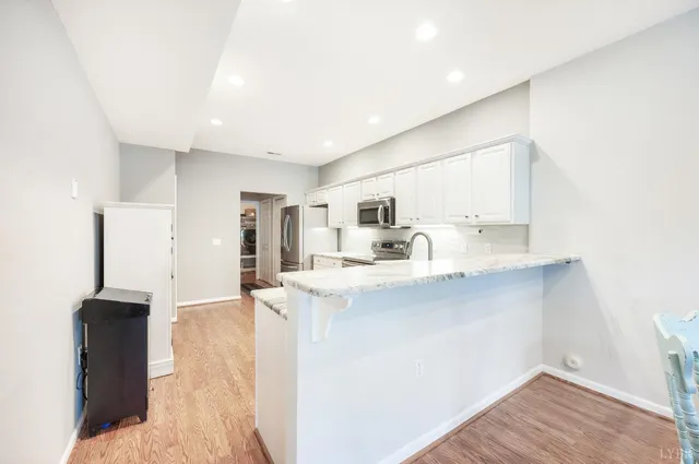 a kitchen with stainless steel appliances a sink a stove a refrigerator cabinets and a dining table