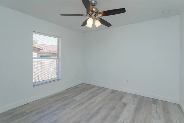 an empty room with a window and a fan