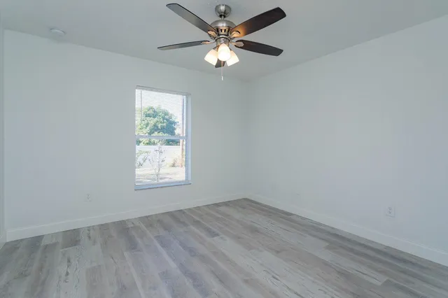 an empty room with a window and a fan