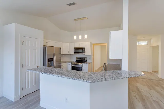 a kitchen with stainless steel appliances granite countertop a refrigerator a sink a stove and oven