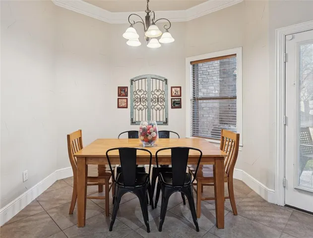 a view of a dining room with furniture a chandelier and a window