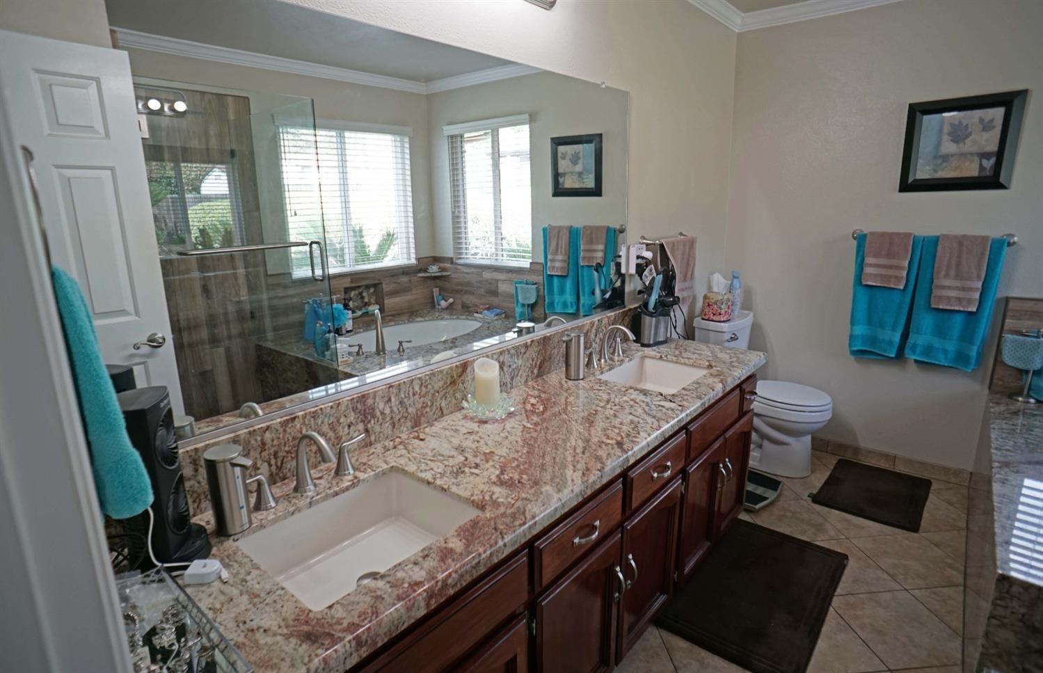 2197 Polson Avenue Clovis, CA 93611 - Photo 29 of 42 a bathroom with a granite countertop sink a toilet a mirror and shower