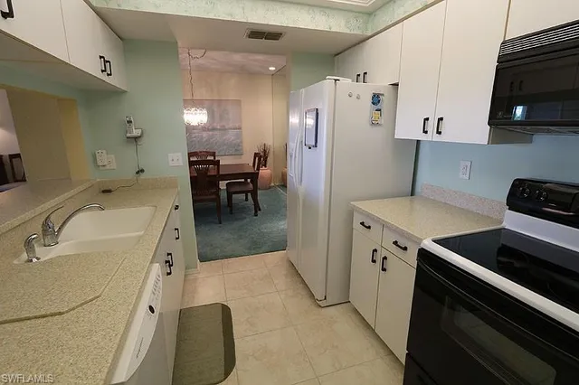 a kitchen with a sink a refrigerator and chairs