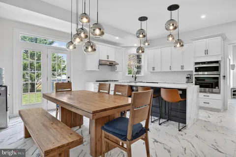 a kitchen with stainless steel appliances a stove a sink island and white cabinets