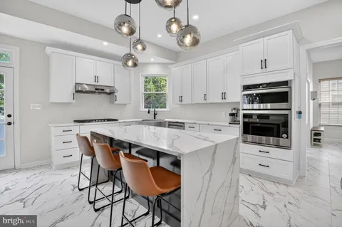 a kitchen with stainless steel appliances granite countertop a stove a refrigerator a kitchen island a dining table and chairs with wooden floor