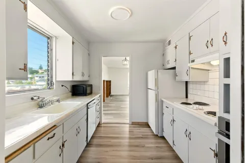 a large white kitchen with stainless steel appliances a stove and a refrigerator
