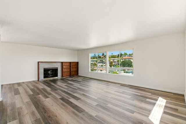 a view of an empty room with a window and fireplace