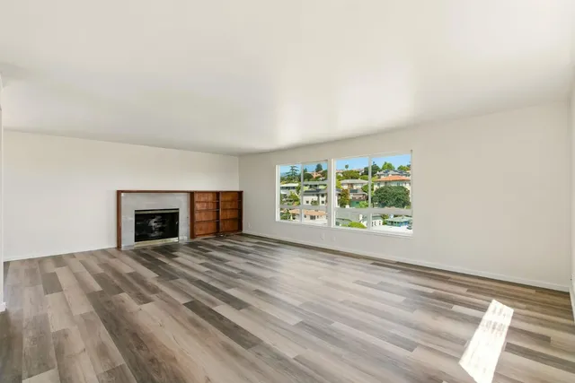 a view of an empty room with a window and fireplace
