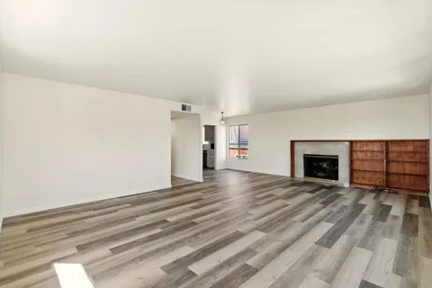 a view of empty room with a fireplace and wooden floor