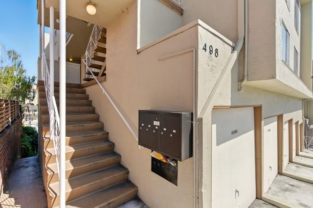 a view of staircase with lots of frames on wall and a window