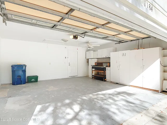 an empty room with a ceiling fan and windows
