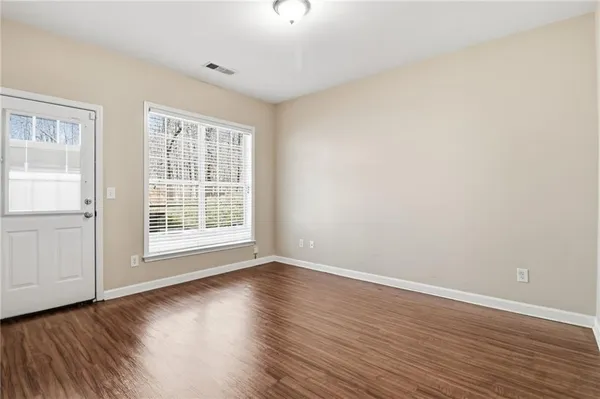 a view of an empty room with wooden floor and a window
