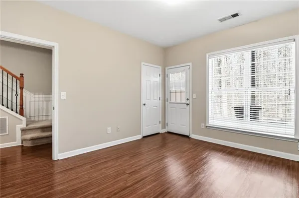 a view of an empty room with wooden floor and a window