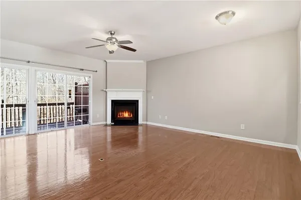 a view of an empty room with wooden floor and a fireplace
