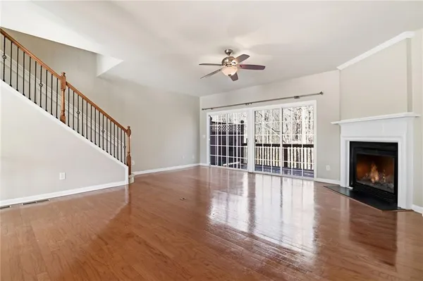 a view of an empty room with wooden floor fireplace and a window
