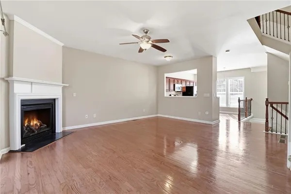 a view of an empty room with wooden floor fireplace and a window
