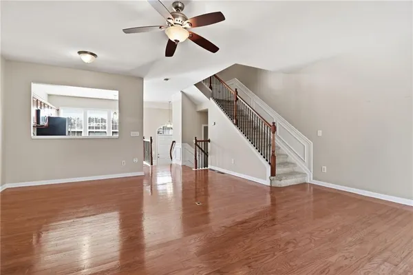 a view of an empty room with wooden floor and a ceiling fan