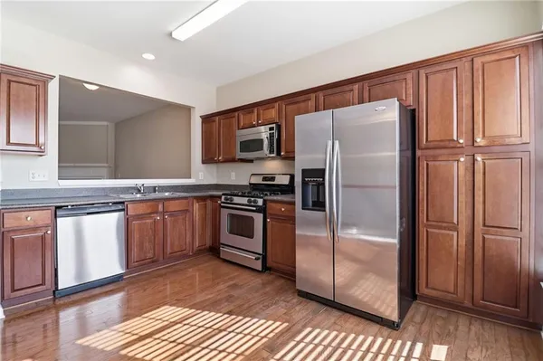 a kitchen with granite countertop stainless steel appliances a refrigerator and cabinets