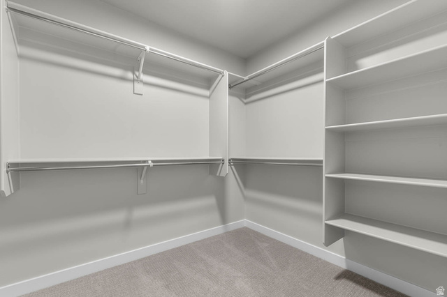 1567 North 3250 West Provo, UT 84601 - Photo 17 of 22 Walk-in closet featuring built-in shelving, multiple hanging rods, and neutral-toned carpeting