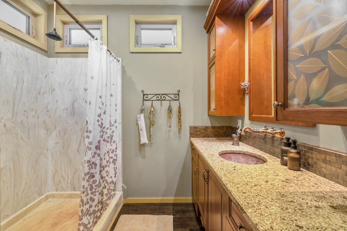 5011 Awawa Road Kalaheo, HI 96741 - Photo 12 of 30 a bathroom with a granite countertop sink a mirror a vanity and shower