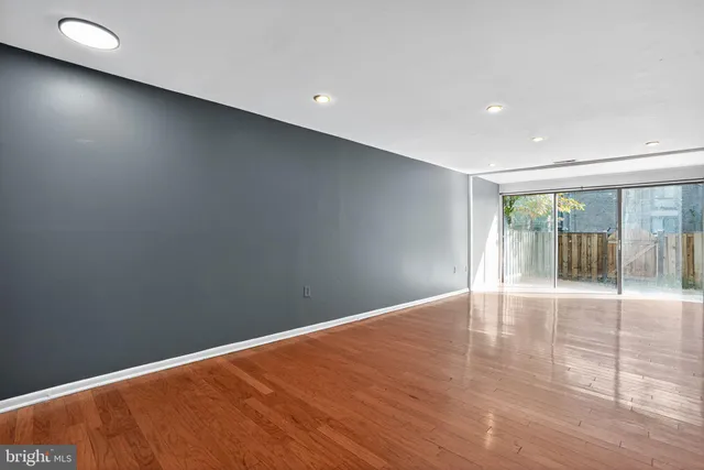 a view of an empty room with wooden floor and a window