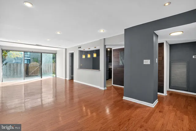 a view of an empty room with wooden floor and a glass door
