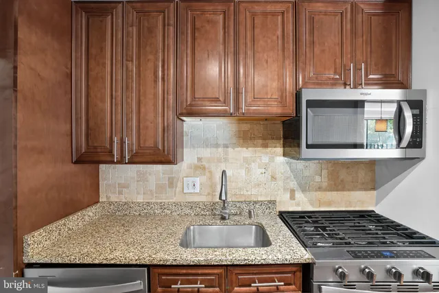 a kitchen with granite countertop wooden cabinets and a stove top oven