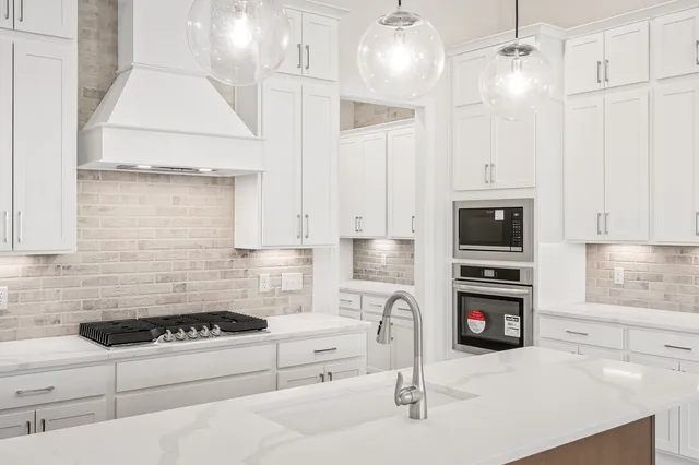 a kitchen with granite countertop a stove a sink and a refrigerator