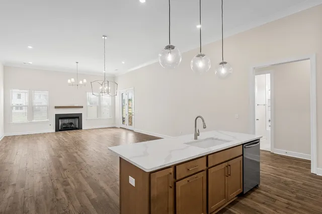 a kitchen with kitchen island a sink stainless steel appliances and living room view
