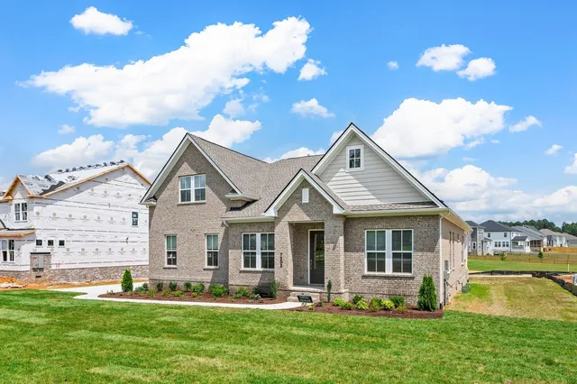 a front view of a house with a garden and trees