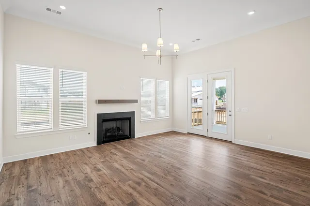 an empty room with fireplace wooden floor and windows