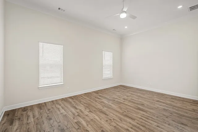 an empty room with wooden floor and windows