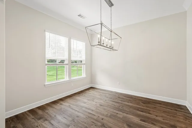 a view of a room with wooden floor exposed radiator and a window