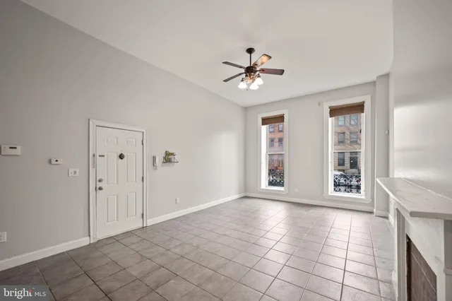 a view of an empty room with chandelier fan and fire place