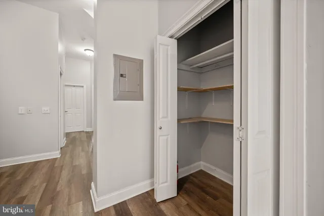 a view of a hallway with wooden floor and a bathroom