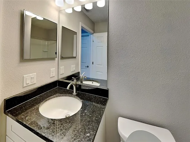 a bathroom with a granite countertop sink and a mirror