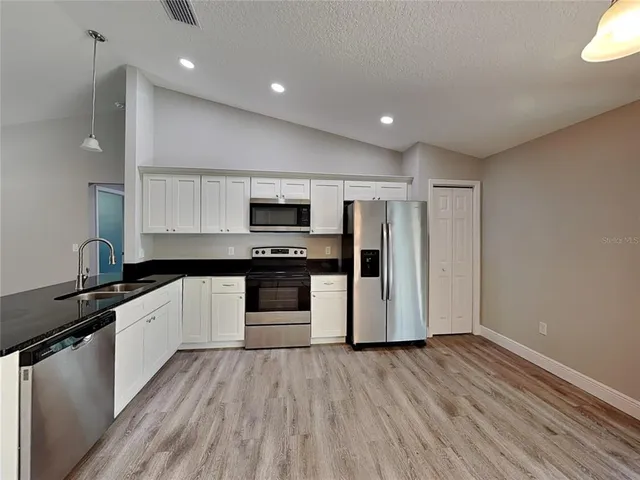 a kitchen with granite countertop a refrigerator and a stove top oven