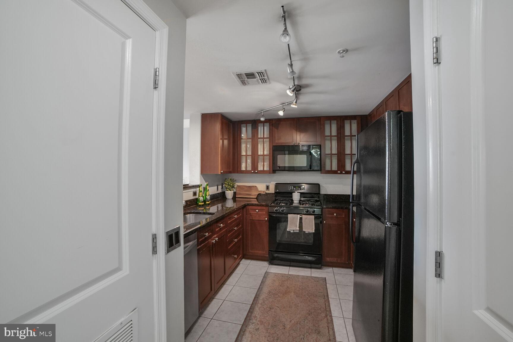 930 Wayne Avenue, Unit 708 Silver Spring, MD 20910 - Photo 14 of 35 a kitchen with stainless steel appliances granite countertop a refrigerator a sink dishwasher a stove and a dining table with wooden floor
