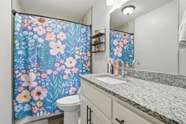 a bathroom with a granite countertop sink and a toilet