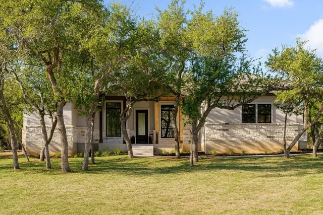 a front view of a house with a large tree