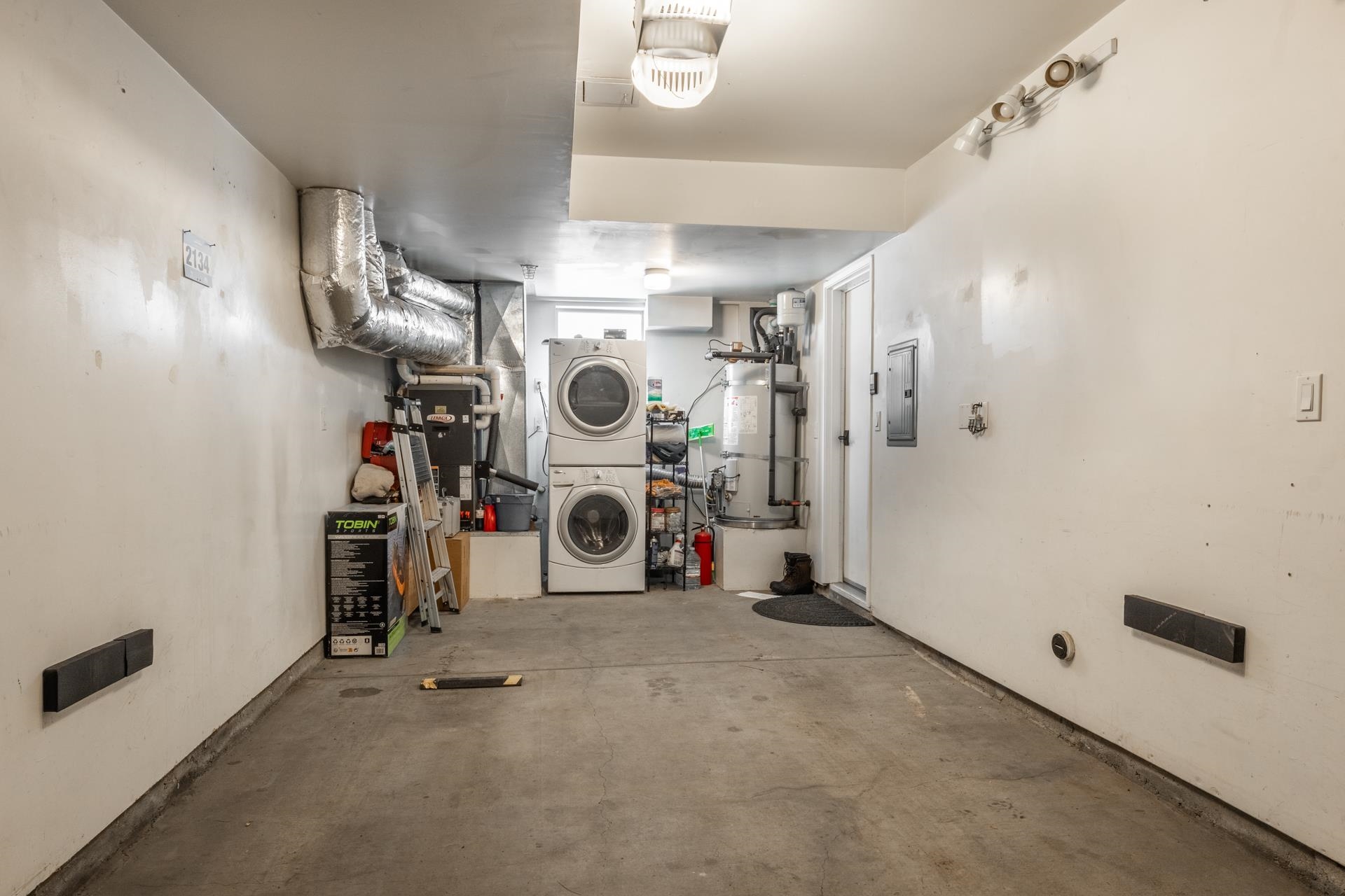 525 Manzanita Road, Unit 2 Mammoth Lakes, CA 93546 - Photo 12 of 13 Washroom featuring stacked washing machine and dryer, secured water heater, unfinished concrete floors, and electric panel
