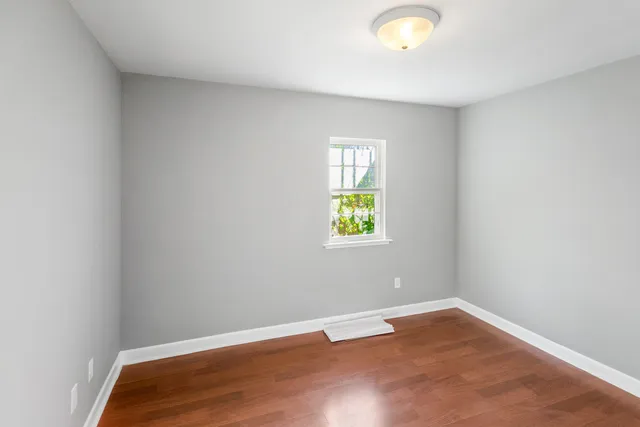a view of an empty room with window and wooden floor