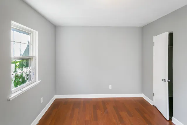 an empty room with a window and wooden floor