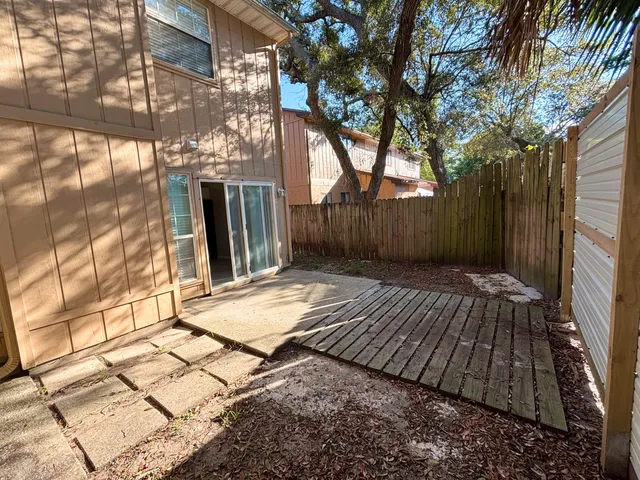 a view of backyard with brick wall and a large tree